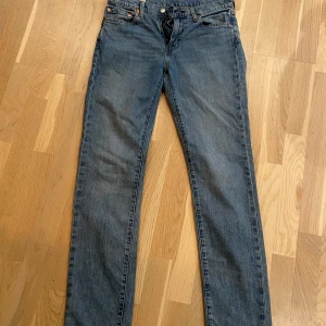  blå jeans från Levi's   - Snygga blå Levi's 511 jeans med en klassisk straight passform. De har en midwaist design och är perfekta för en avslappnad stil. Jeansen har fem fickor och en dragkedja med knappstängning.