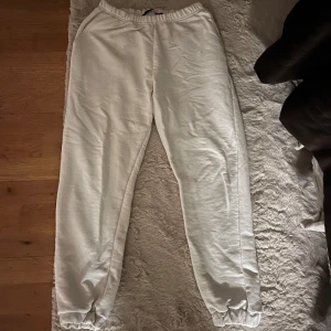 Vita mjukisbyxor - Säljer ett par bekväma vita mjukisbyxor med elastisk midja och muddar vid bensluten. Perfekta för en avslappnad dag hemma eller en snabb tur till affären.