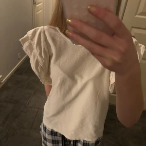 Vit topp med volangärmar - Säljer en söt vit topp med volangdetaljer på ärmarna. Toppen har en lös passform och är perfekt för en avslappnad stil. Den är tillverkad i ett mjukt material som känns skönt mot huden.💗💗