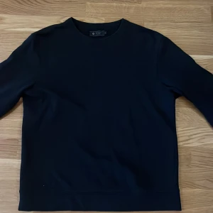 Mörkblå tröja från Riley - Säljer en stilren mörkblå tröja från Riley i storlek M. Tröjan har långa ärmar och en klassisk rund halsringning. Perfekt för en minimalistisk look.