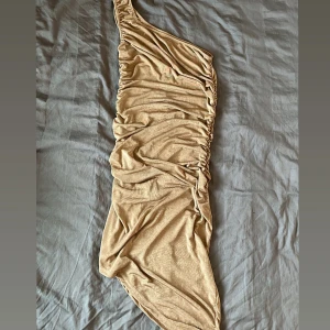 Guld one-shoulder klänning - Snygg guld one-shoulder klänning med draperad design. 