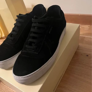 Svarta sneakers med vit sula - Snygga svarta Axel Arigato med vit sula och snörning. Perfekta för en stilren look. Skorna har en klassisk design med diskreta detaljer.