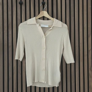 Beige ribbad kofta från Selected Femme - Säljer en stilren beige ribbad kofta från Selected Femme. Koftan har trekvartsärmar och knappar framtill, perfekt för en elegant look. Den är tillverkad i ett mjukt material som ger en skön passform. storlek Xs