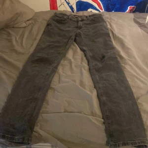 Grå jeans från Tommy Hilfiger - Snygga grå jeans från Tommy Hilfiger med klassisk design. De har en knappgylf och märkets logga på bakfickan. Perfekta för en stilren look. Skriv i DM för mer bilder eller funderingar storleken där det står 32 är jag inte säker på i byxorna står det att det är 164