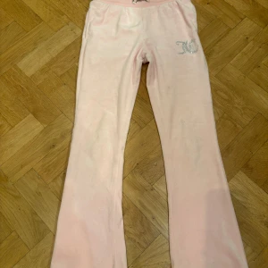 Rosa mjukisbyxor från Juicy Couture - Säljer ett par rosa mjukisbyxor från Juicy Couture med glittrig JC-logga på framsidan. Byxorna har en bekväm passform med dragsko i midjan och bakfickor. Perfekta för en avslappnad stil/stockhomsstil❤️🤞😘