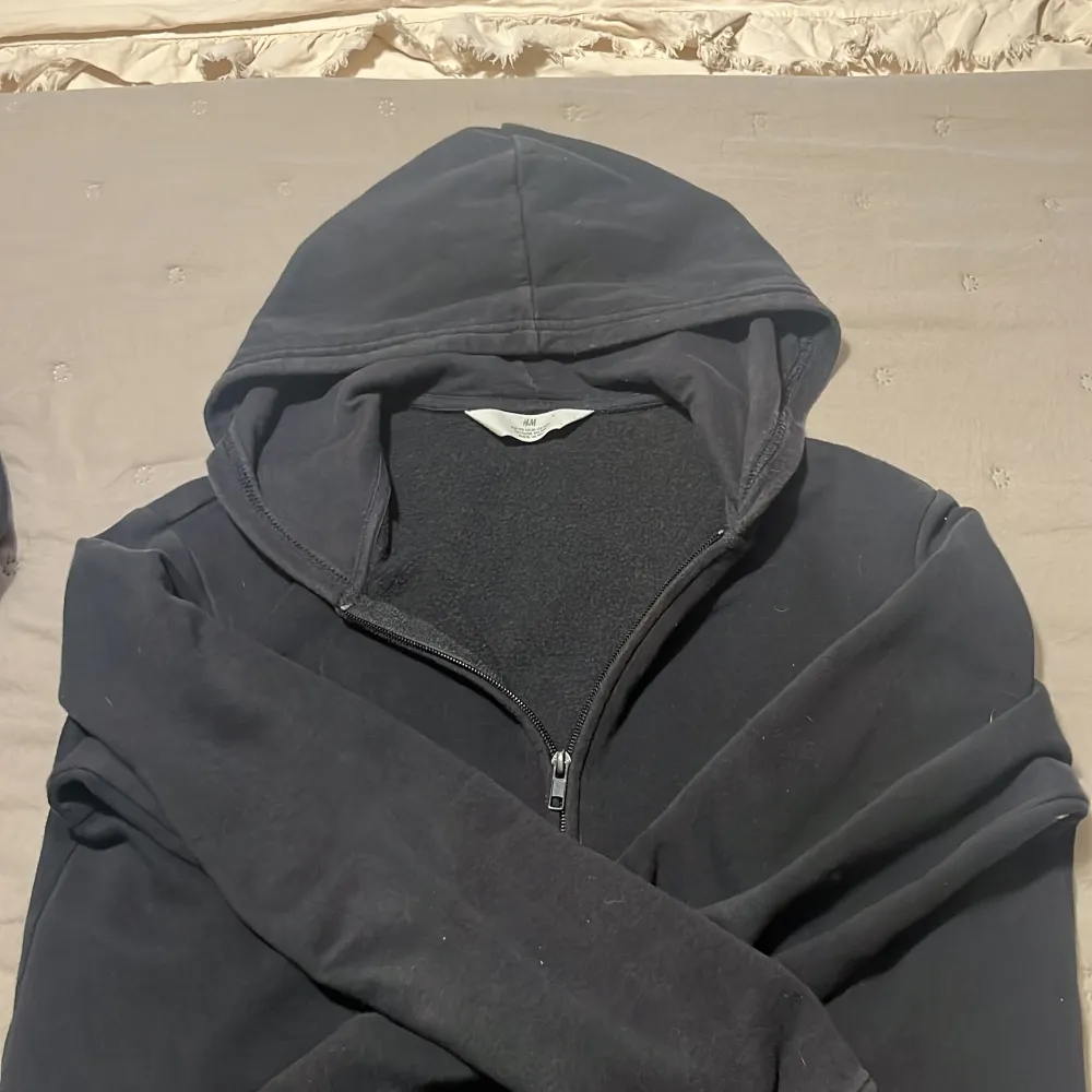 Säljer en klassisk svart hoodie från H&M med dragkedja och huva. Perfekt för en avslappnad stil. Tröjan har långa ärmar och är tillverkad i ett mjukt material för extra komfort.. Neuletakit & Villapaidat.