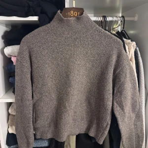 Gråbrun polotröja från H&M - Säljer en stilren grå polotröja från H&M. Tröjan har en hög krage och långa ärmar, storlek XS .perfekt för kyligare dagar. Den är mjuk och bekväm, vilket gör den till ett utmärkt val för både vardag och avslappnade tillfällen.