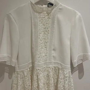 Vit spetsklänning med kort ärm - Elegant vit blus med vackra spetsdetaljer. 