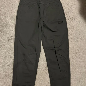 Svarta mjukisbyxor från EA7 Armani - Säljer ett par svarta mjukisbyxor från EA7 Armani. Byxorna har en elastisk midja och två sidofickor. Perfekta för en avslappnad stil.