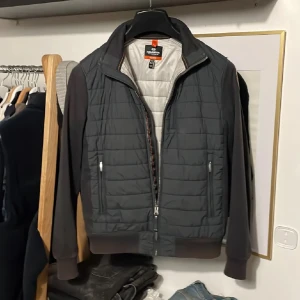 Grå jacka från Parajumpers - Säljer en snygg grå jacka från Parajumpers med quiltad design och dragkedja. Jackan har långa ärmar och en cool patch på ärmen. Perfekt för höst och vår med sin stilrena look och bekväma passform. Annonsen är från simpan00 då jag hjälper han sälja den!