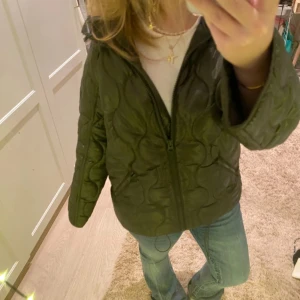 Grön quiltad jacka - Säljer en snygg grön quiltad jacka med dragkedja. Jackan har en cool design med långa ärmar och en bekväm passform. Perfekt för att hålla stilen i kyligare väder. Egentligen storlek xs men skulle säga att den passar S-M. Helt ny med prislapp kvar!