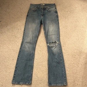 Blå jeans med slitning - Snygga blå jeans från Perfect Jeans med en cool slitning på ena benet. De har en klassisk femficksdesign och en knappgylf. Perfekta för en avslappnad stil.