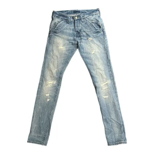 Blå jeansbyxor från Lee - Snygga blå jeansbyxor från Lee med slitna detaljer för en trendig look. Byxorna har en klassisk ficksdesign och knappgylf. Perfekta för en avslappnad stil. I 100% bomull w27 L33