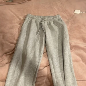 Grå mjukisbyxor med snörning - Säljer ett par bekväma grå mjukisbyxor med elastisk midja och snörning. Perfekta för en avslappnad dag hemma eller på språng. Byxorna har en klassisk design med raka ben och är tillverkade i mjukt material.
