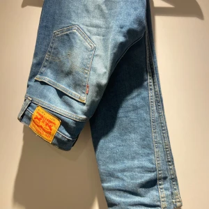 Levis 511 - Snygga blå jeans från Levi's med klassisk femficksdesign och en ikonisk läderpatch på baksidan. De har en straight passform och är perfekta för en avslappnad stil. Jeansen har en lätt tvättad look som ger dem en cool vintagekänsla.