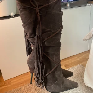 Bruna mockastövlar med fransar - Snygga bruna stövlar i mocka med hög klack och spetsig tå. De har dekorativa fransar och snörning som ger en unik look.