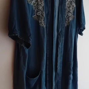 Blå denimklänning med broderi från Iconic - Säljer en snygg blå denimklänning från Iconic i storlek 14. Klänningen har korta ärmar och vackra blommiga broderier på framsidan. Perfekt för en avslappnad vår- eller sommarlook. Den har en loose passform och är superbekväm att bära. Passar både till vardags och festligare tillfällen!