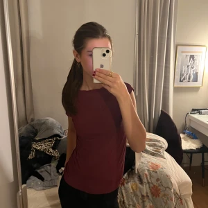 Vinröd kortärmad topp - Säljer en stilren vinröd topp med korta ärmar. Perfekt för en avslappnad look. Passar bra till både jeans och kjol.