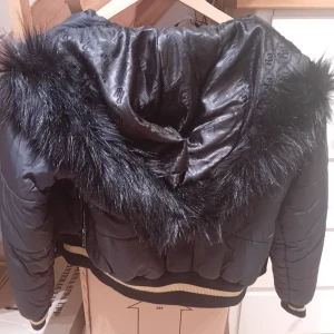 Svart pufferjacka med pälsdetaljer från Rocawear - Lägger upp denna super fina unika y2k 2000s jacka från roca wear med guld detaljer o päls som jag sytt på själv. Är osäker på om jag vill sälja sp buda! Den är I m men skulle mer säga som s