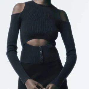 Svart ribbad topp från Zara - Snygg svart ribbad topp från Zara med cut-out detaljer vid axlarna och knappar framtill. Helt ny