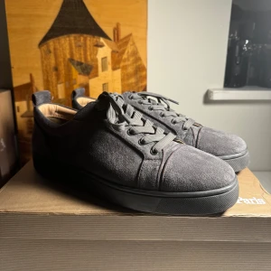 Gråa Christians Louboutins - Säljer ett par snygga grå loubs i mocka med en cool röd sula. De har snörning och en stilren design som passar perfekt till både vardag och fest. Skorna är i mycket bra skick och redo för nya äventyr!