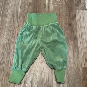 Gröna babybyxor från Hello Baby - Säljer ett par mjuka och bekväma gröna babybyxor från Hello Baby. Byxorna har breda muddar vid midjan och bensluten för extra komfort. Perfekta för små äventyrare!
