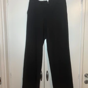 Svarta byxor från La Redoute - Snygga svarta byxor från La Redoute med en klassisk design. Byxorna har en rak passform och är perfekta för en stilren look. De är tillverkade i ett bekvämt material som passar för olika tillfällen.