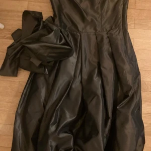 Klänning fZara oanvänd - Snygg klänning i mörkgrön metallicfärg från Zara. Klänningen är i en figursydd modell med band i midjan. Perfekt för festliga tillfällen. Stlk S. Oanvänd.  Ev. frakt betalas av köparen.