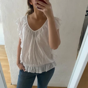 Vit blus med volangdetaljer - Säljer en söt vit blus med volangdetaljer från saint tropez! Passar XS-M