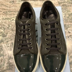 Svarta sneakers från Lanvin - Snygga svarta sneakers från Lanvin i mycket bra skick. De har en glansig tå och snörning framtill. Perfekta för både vardag och fest! Nästan helt nya använda kankse ett 10tal gånger