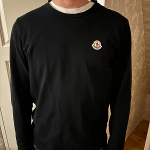 Svart långärmad tröja från Moncler - Säljer en stilren svart långärmad tröja från Moncler. Den har en liten logga på bröstet och är perfekt för både vardag och fest. Tröjan är i bra skick och passar till alla tillfällen. Perfekt för höst och vår!