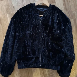 Svart pälsjacka, fuskpäls med paljetter från Lindex - Snygg fuskpäls med paljetter från Lindex i storlek Xs. Perfekt att lyfta en outfit och till jul/ nyårsstassen!  Nypris 499kr. Endast använd två gånger och i mycket fint skick!