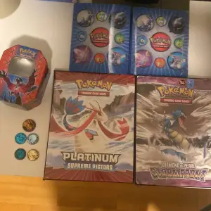 Selling a Pokemon Trading Card Game set with two big folders and 2 small. Also includes a red Pokemon-themed empty tin can and several collectible coins. Perfect for collectors or Pokemon fans! 🎴