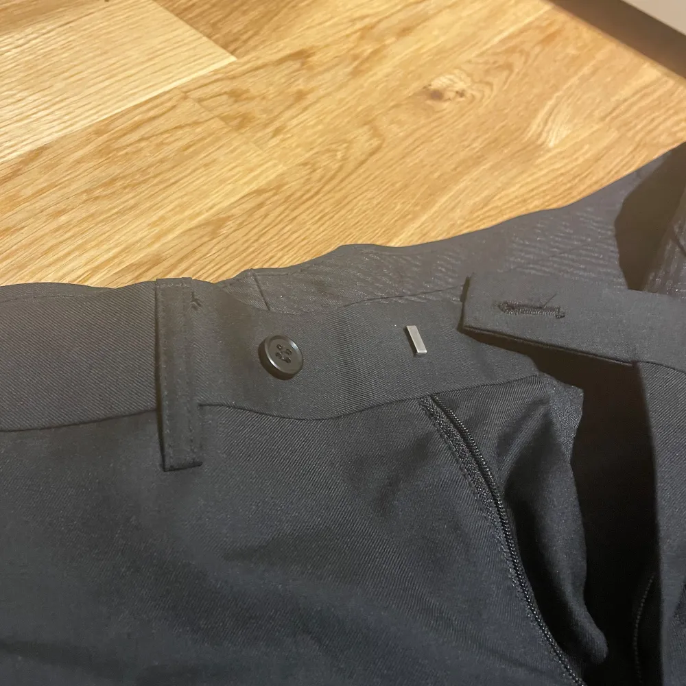 Snygga svarta kostymbyxor från Batistini i en mix av polyester och ull. Byxorna har en klassisk straight passform och är perfekta för en stilren look. De har knappar bak och en diskret dragkedja framtill.. Farkut & Housut.
