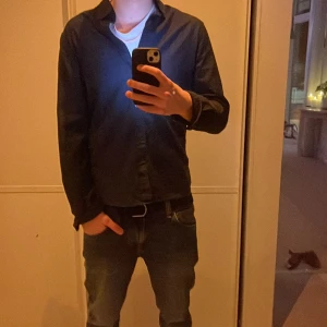 Mörkblå skjorta från Dressmann - Säljer en stilren mörkblå skjorta från Dressmann i slim fit. Perfekt för en elegant look. Skjortan har långa ärmar och en klassisk krage.