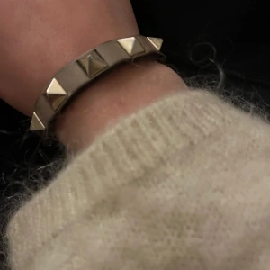 Valentino armband  - Säljer mitt beiga valentino armband med guldiga nitar. Självklart äkta. Det är slitet men det syns inte när man har på sig det. Nypris ca 2380 men eftersom det är slitet så säljer jag det billigt.❤️