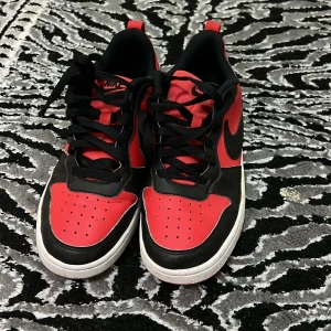 Nike sneakers i rött och svart - Säljer ett par snygga Nike sneakers i rött och svart. De har en klassisk design med svart snörning och vit sula. Perfekta för både vardag och träning. Skorna är i bra skick och redo för nya äventyr!