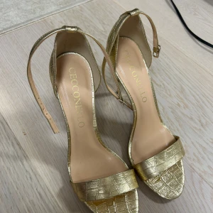Guldiga klackskor från Cecconello - Snygga guldiga klackskor från Cecconello i storlek 39. De har croc design och en smal klack 10 cm. Skorna är i mycket bra skick och aldrig använts enbart provat. 