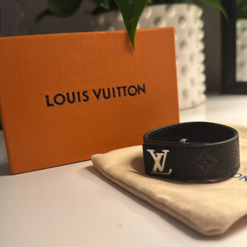 Säljer ett stilrent svart armband  från Louis Vuitton i skinn. Bältet har en elegant LV-logga i silver och kommer med originalförpackning och dustbag. Perfekt för att ge en lyxig touch till vilken outfit som helst. Passar både till vardag och fest!. Övrigt.