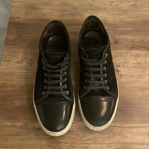 Svarta sneakers från Lanvin - !!Priset är inte spikat kan sänkas vid snabb och smidig affär!! Säljer ett par svarta sneakers från Lanvin i bra skick. De har en stilren design med snörning och en vit sula som ger en snygg kontrast. Perfekta för både vardag och fest! Skorna är bekväma och passar till det mesta i garderoben. 