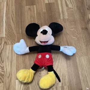 Mjukisdjur av känd muskaraktär - Säljer en mjuk och gosig mjukisdjur av en känd muskaraktär från Disney. Den har svarta öron, röd byxa med vita knappar, gula skor och vita handskar. Perfekt för barn eller som samlarobjekt för Disney-fans.