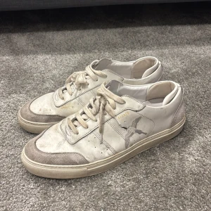 Vita sneakers från Arigato - Snygga vita sneakers från Arigato med snörning och en diskret fågeldetalj på sidan. Skorna har en klassisk design med en bekväm sula och är perfekta för vardagsbruk.