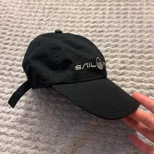 Svart Sail Racing keps - Snygg svart keps från Sail Racing “Bowman Logo Cap”. Har justerbar rem baktill och tillverkad i 100% bomull. Aldrig kommit till användning