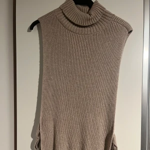 Beige stickad väst  - Säljer en stickad väst från hm. Onesize storlek i fint skick endast använd några gånger. Polokrage som går att vika ner och  knytband på sidorna.