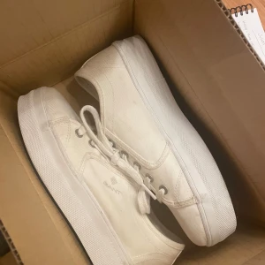 Vita sneakers från Gant - Snygga vita sneakers från Gant med klassisk design och snörning. Perfekta för en stilren look. Tillverkade i ett slitstarkt material med bekväm passform.