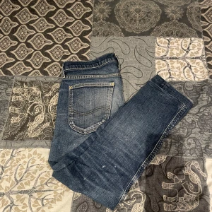 Lee jeans - Säljer ett par blå jeans med snygga slitningar och klassisk femficksdesign från märket Lee. De har en knapp och dragkedja framtill. Perfekta för en avslappnad stil. Storleken är 29/29. (Köpta för 899 säljer för 349)