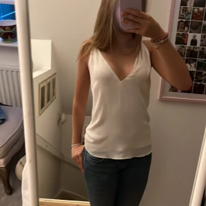 Vit topp med korsande band i ryggen - Säljer en vit topp med v-ringning och smala axelband. Perfekt för sommardagar eller en utekväll. Toppen har en elegant och enkel design som passar till det mesta. Den är i mycket bra skick!💕