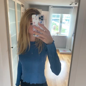 Blå långärmad - En oanvänd blå långärmad med ribbat material och våg-kanter  (Vet inte vad som hände med färgen på bild 2) 