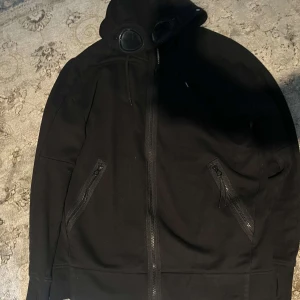 C.P. Company zip hoodie - Jag säljer min cp company tröja eftersom att jag har bytt stil och att jag inte vill ha den längre, tröjan är köpt äkta och har använts ett fåtal gånger, tröjan är i storlek L men passar också folk som har storleken M. 