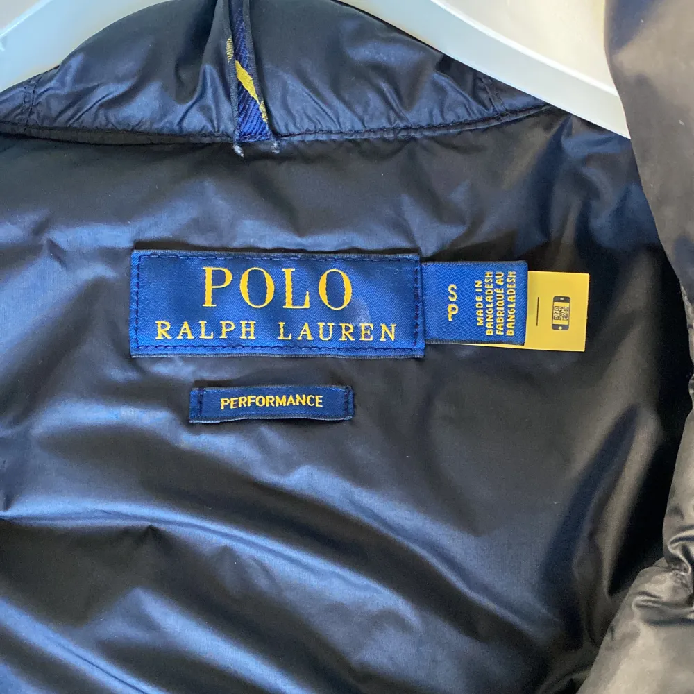 Säljer en snygg svart dunväst från Polo Ralph Lauren. Västen har en quiltad design med dragkedja framtill och två praktiska fickor med dragkedjor. Perfekt för höst och vår när du vill hålla dig varm men ändå se stilren ut.. Jackor.